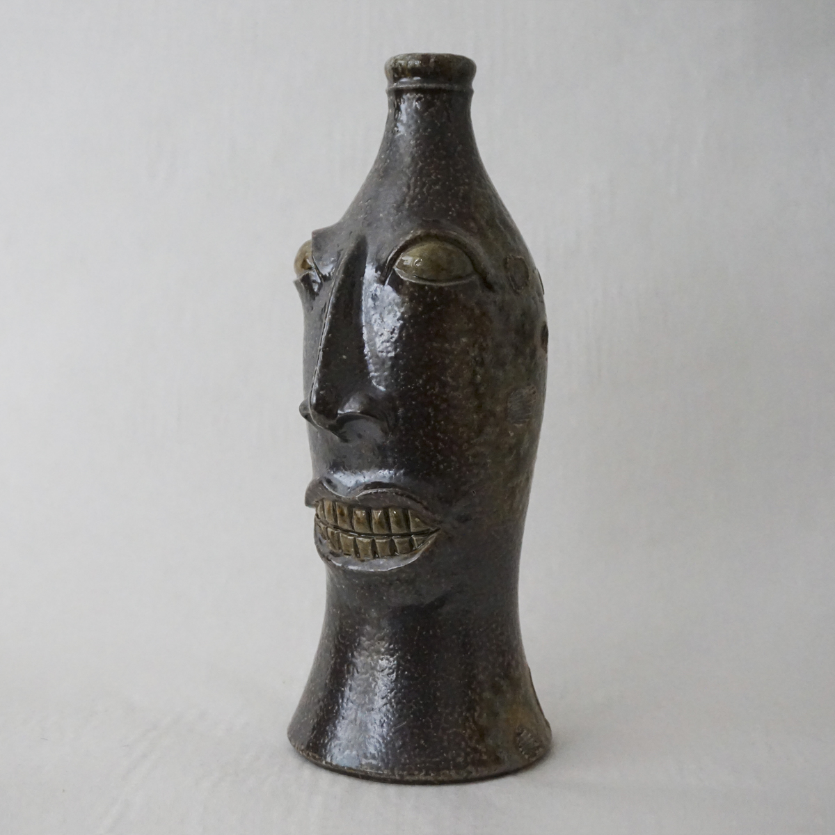 full view image of a sculpture of a face in the shape of a coke bottle